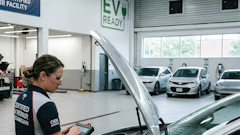 Certified EV repair technician inspecting electric vehicle in modern charging facility