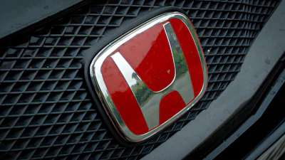 Red Honda emblem on vehicle grille with chrome trim