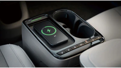 Smartphone with green lightning bolt charging icon displayed on wireless charging pad in car console