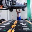 Automotive technician working under vehicle lifted on green hydraulic lift in professional service garage