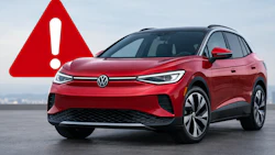 Red Volkswagen ID.Buzz electric SUV with warning alert symbol on gray surface