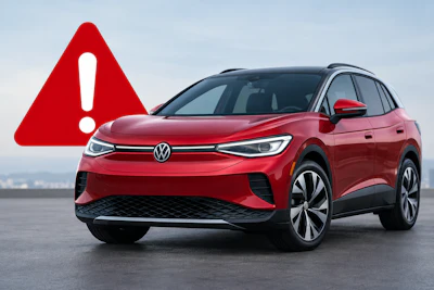 Red Volkswagen ID.Buzz electric SUV with warning alert symbol on gray surface